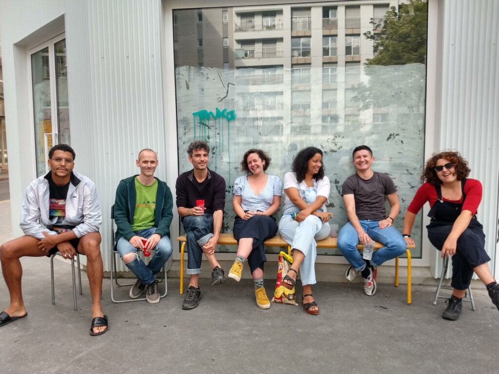 Photo couleur : 7 personnes devant le local de Paillettes & Cambouis, en juullet 2023, avant son ouverture